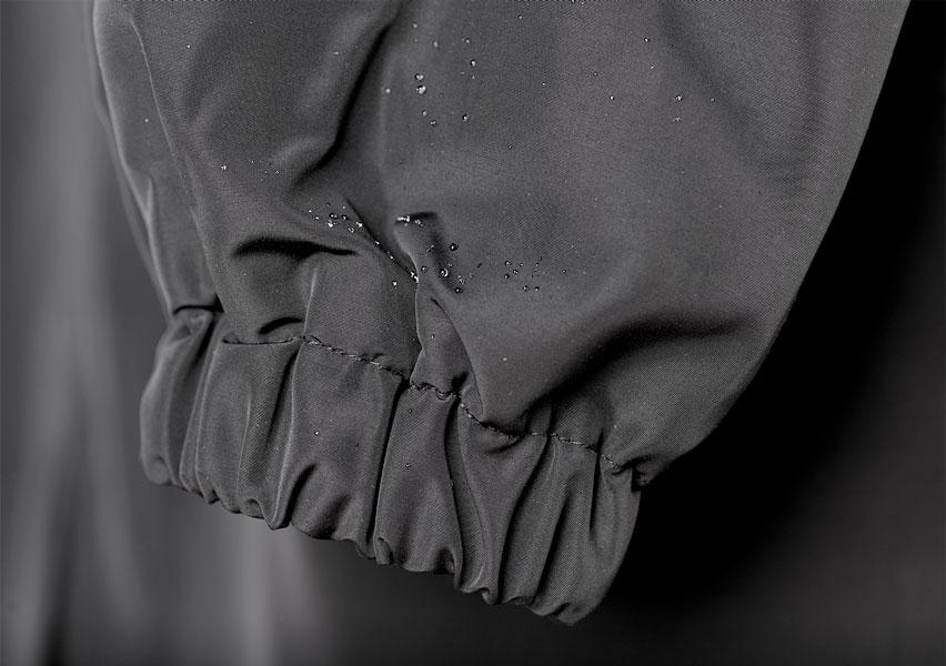 Waterproof raincoat cuff detail with elastic hem and water droplets on dark fabric