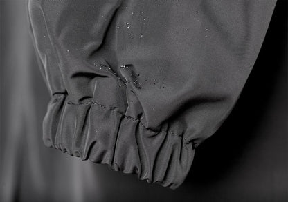 Waterproof raincoat cuff detail with elastic hem and water droplets on dark fabric