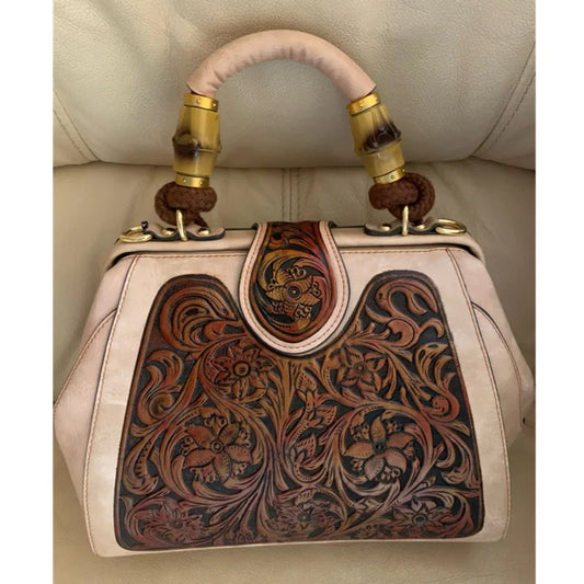 Beige leather handbag with front carved floral panel and gold-tone ring handles