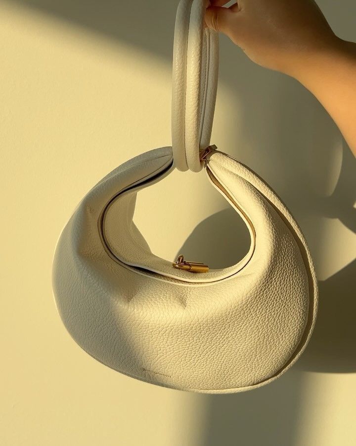 Off-white pebbled convertible handbag with top handle and crescent shape
