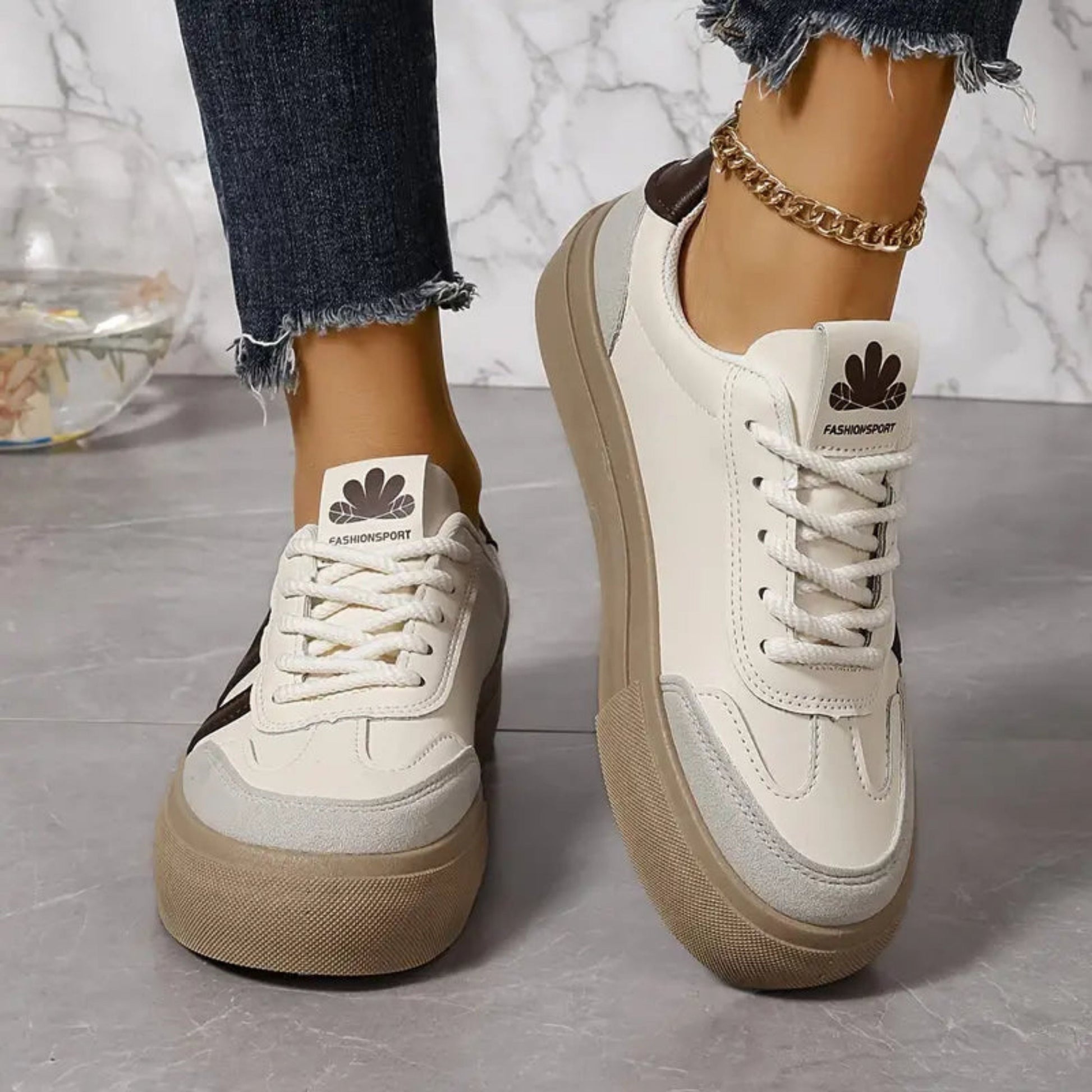 White chunky lace-up sneakers with tan platform sole and brown accent stripe near heel.