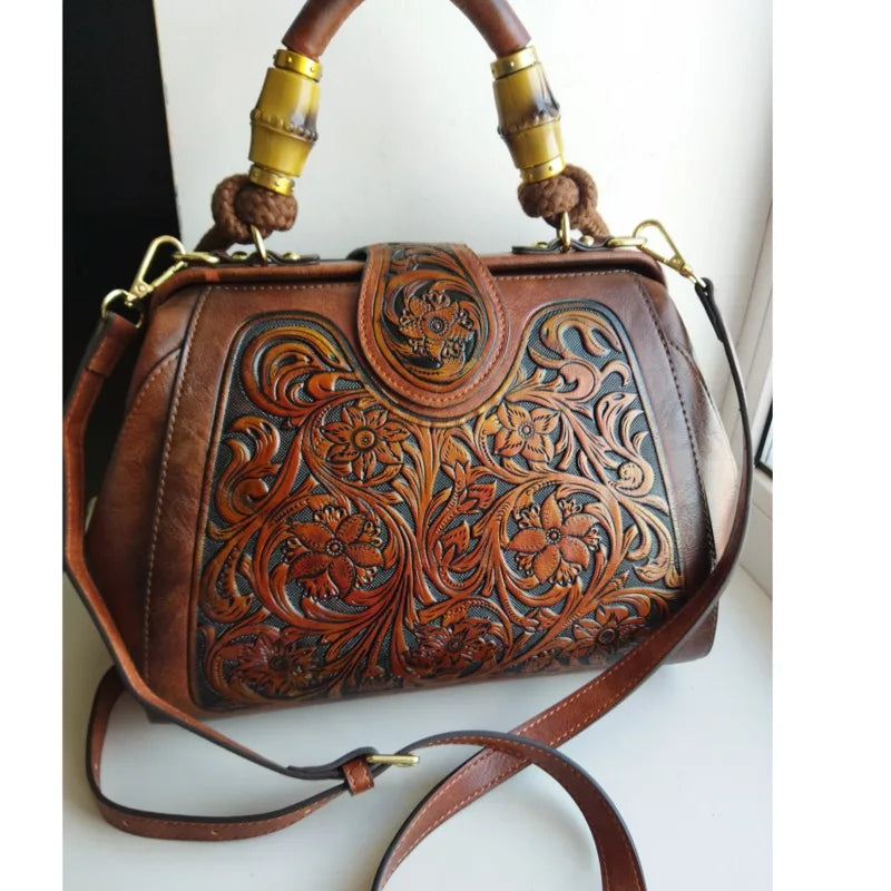Brown leather handbag with carved floral design, gold-tone hardware, and crossbody strap