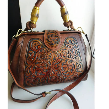 Brown leather handbag with carved floral design, gold-tone hardware, and crossbody strap