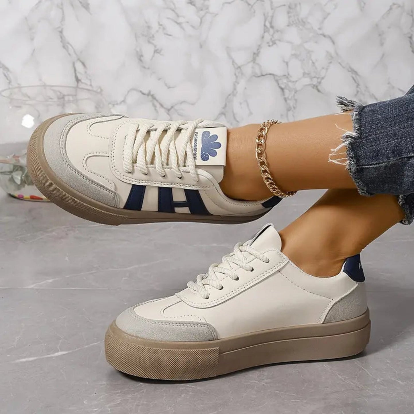 White low-top sneakers with blue 3-stripe sides, lace-up front, tan rubber sole.